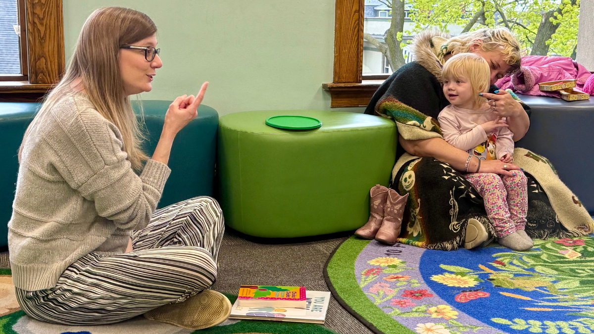 staff member leading songs during baby play club