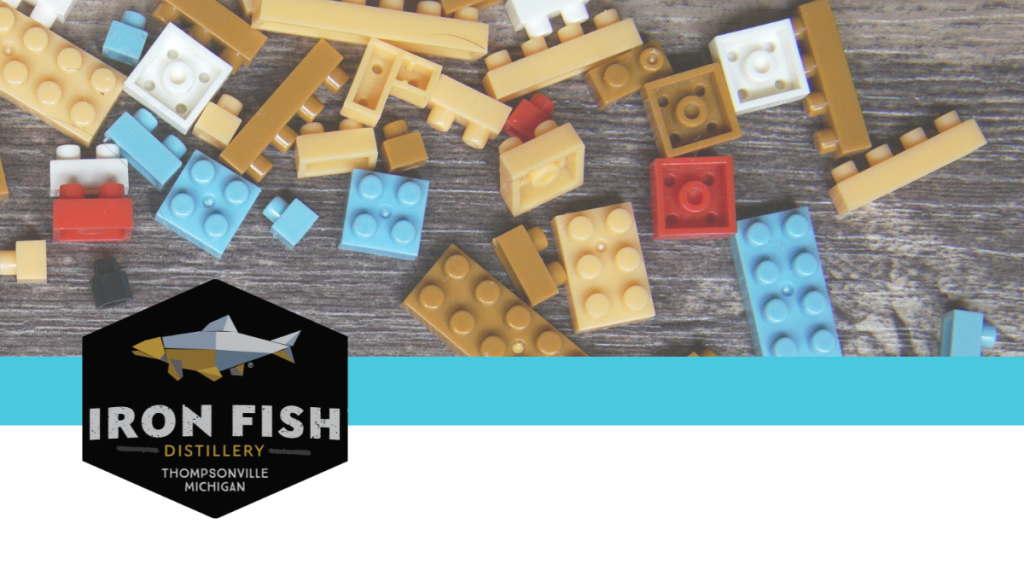 lego pieces scattered about and the Iron Fish Distillery Logo